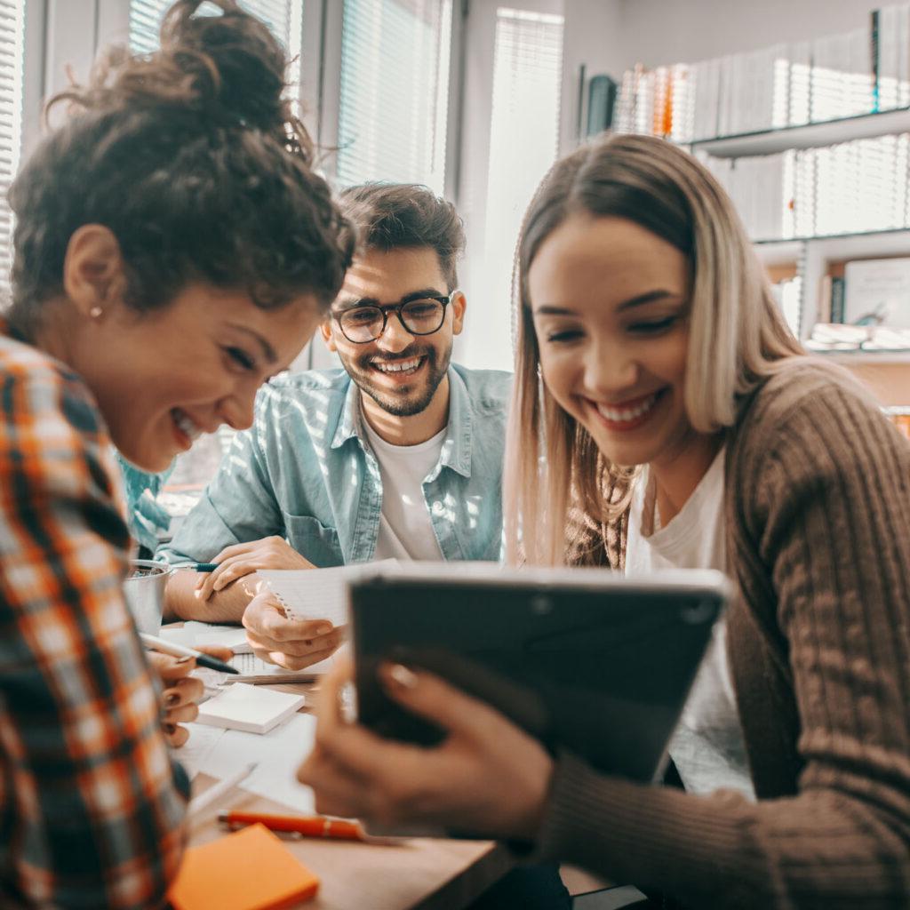 Three students looking at a tablet computer screen.